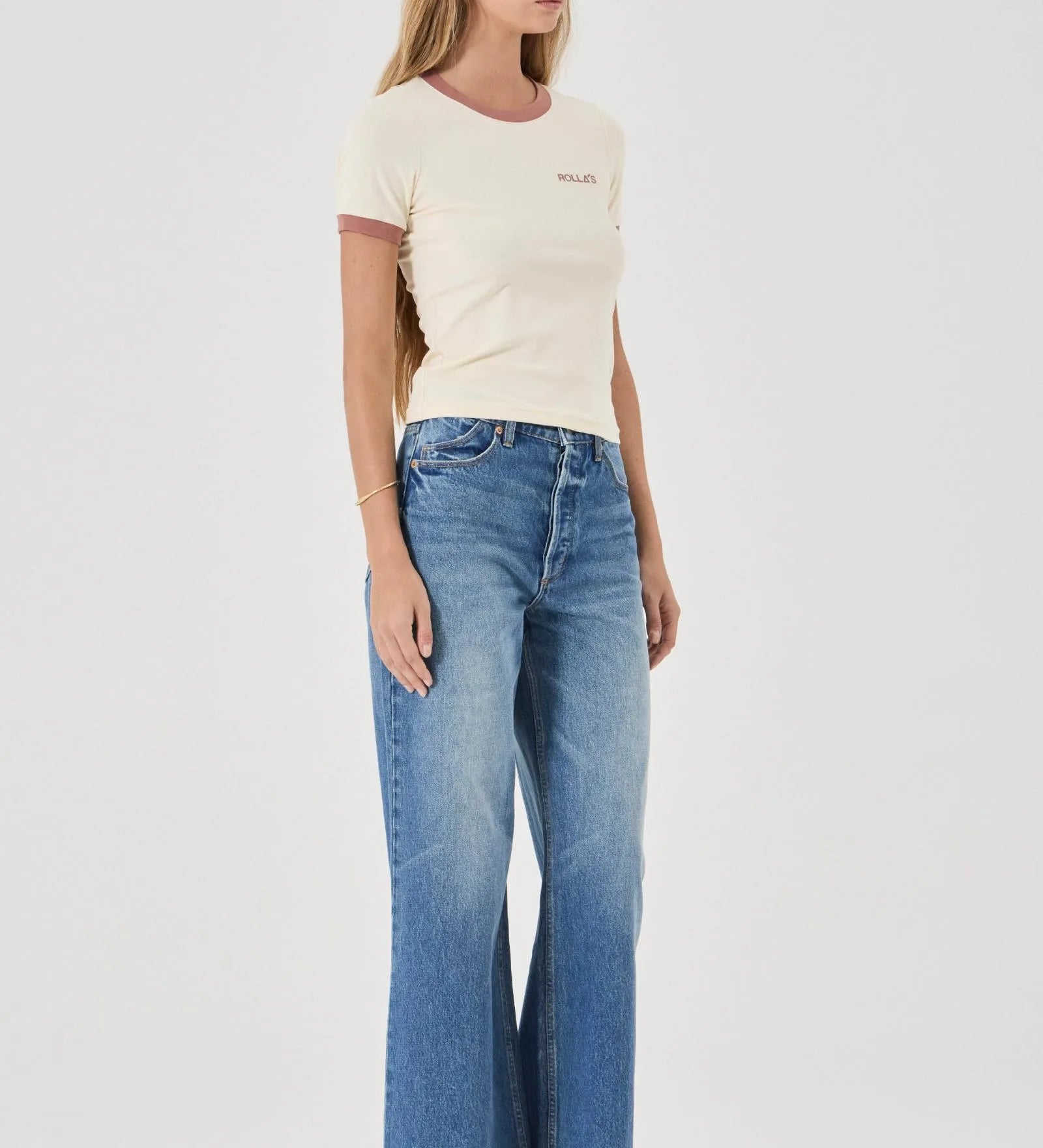 Woman wearing a cream t-shirt and blue jeans on a white background