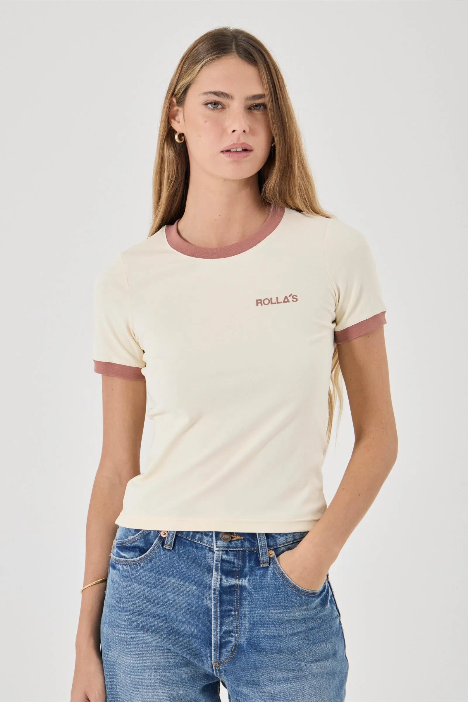 Woman wearing a cream t-shirt with maroon accents and blue jeans on a white background