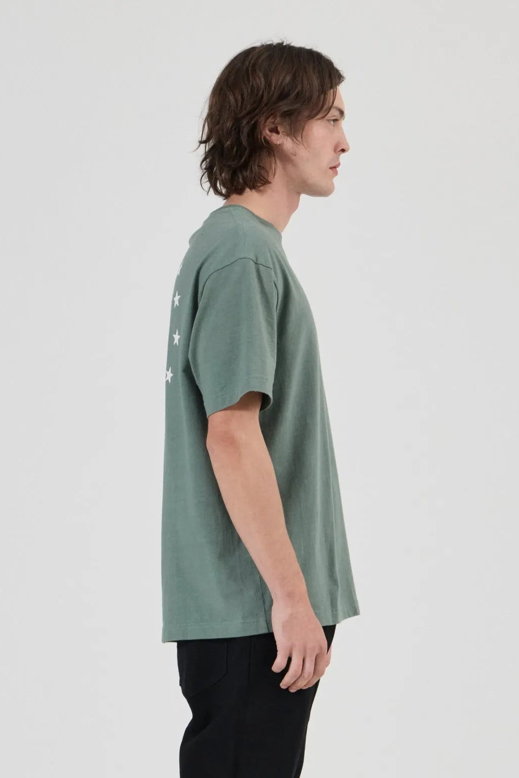 Person wearing a green t-shirt and black pants on a white background