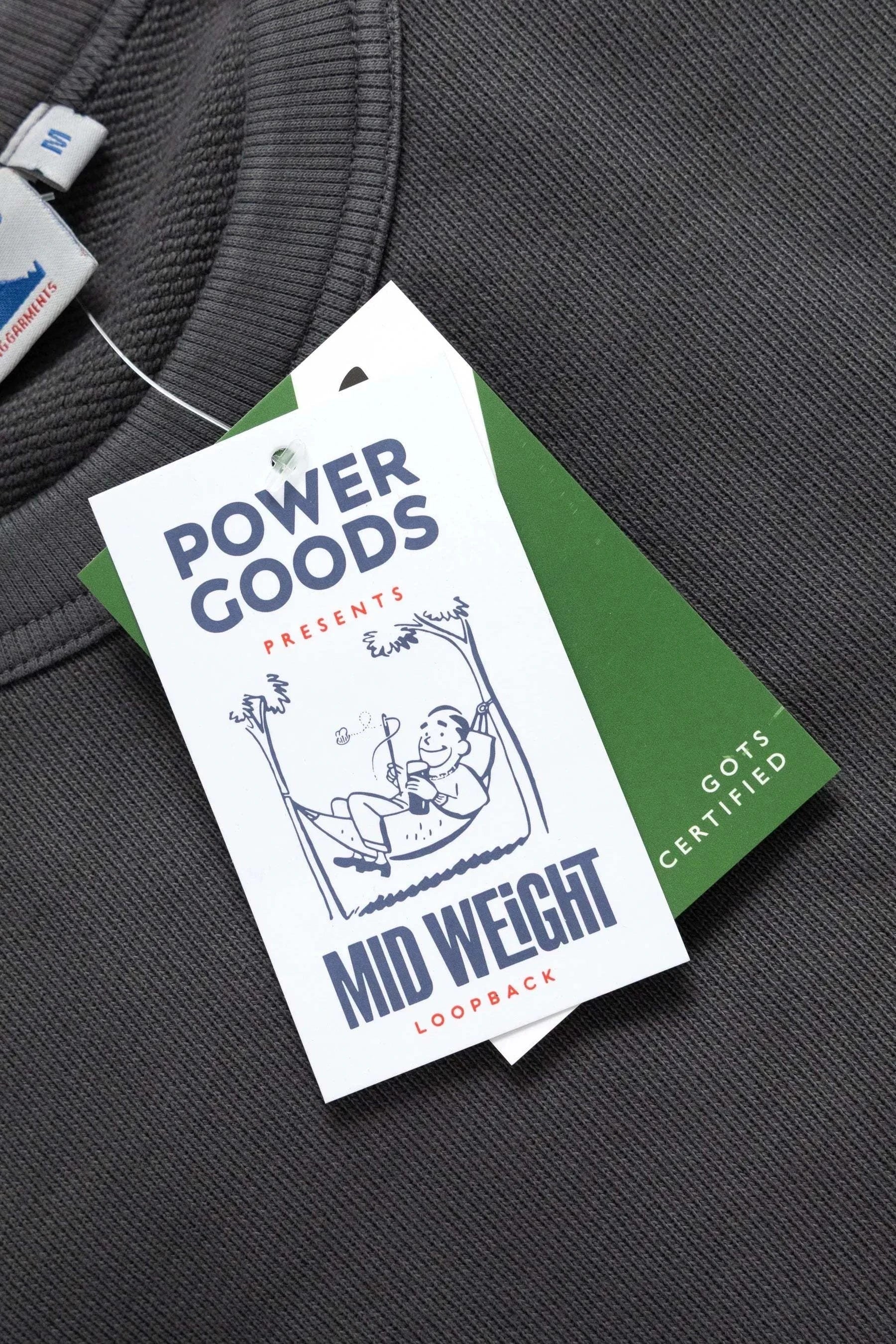 Clothing tag with 'Power Goods' branding on a gray background