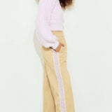 Woman wearing a light pink top and beige pants with a white background