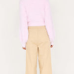 Person wearing a pink sweater and beige pants on a white background