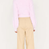 Person wearing a pink sweater and beige pants on a white background