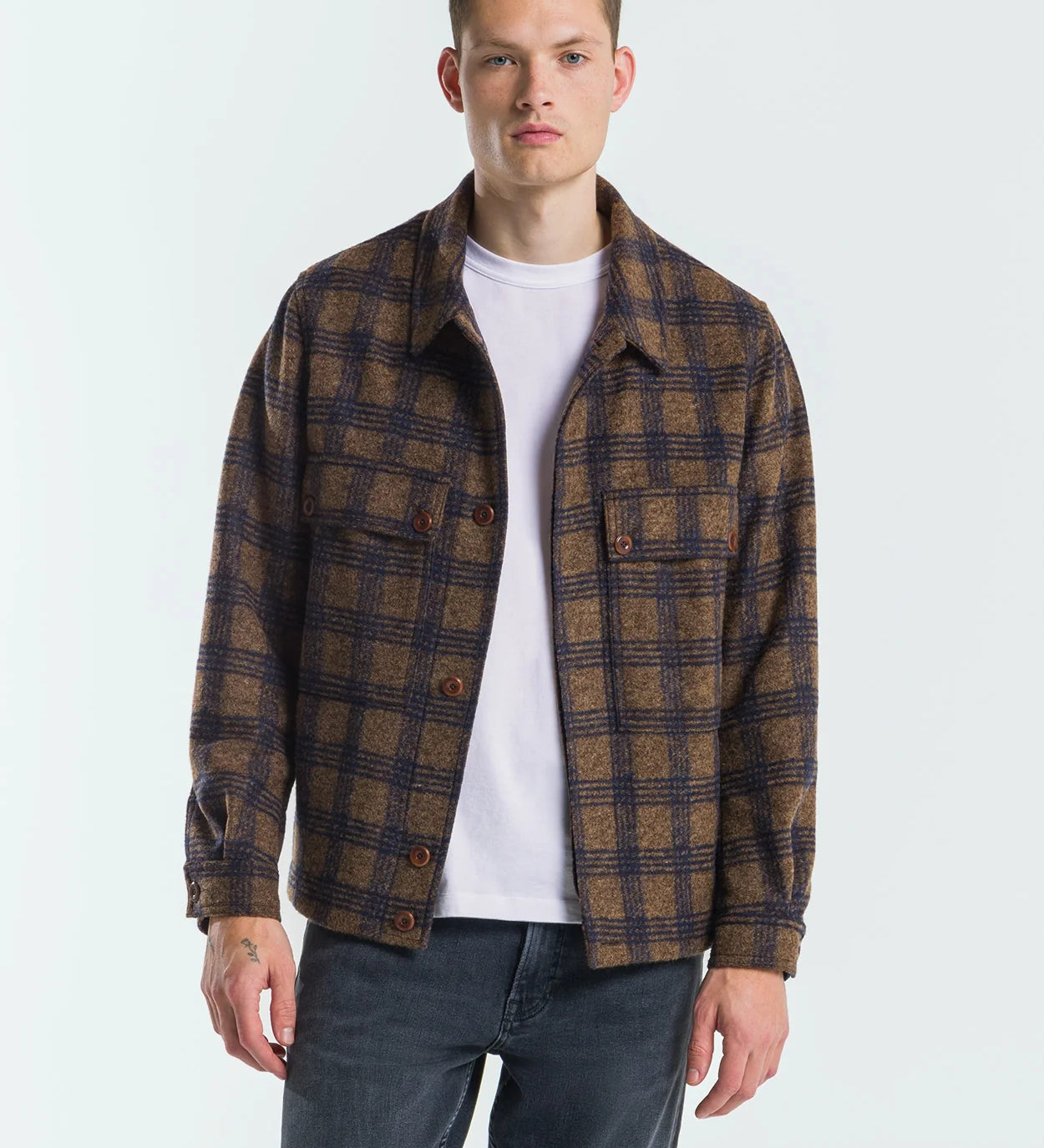 Man wearing a plaid shirt over a white t-shirt on a white background