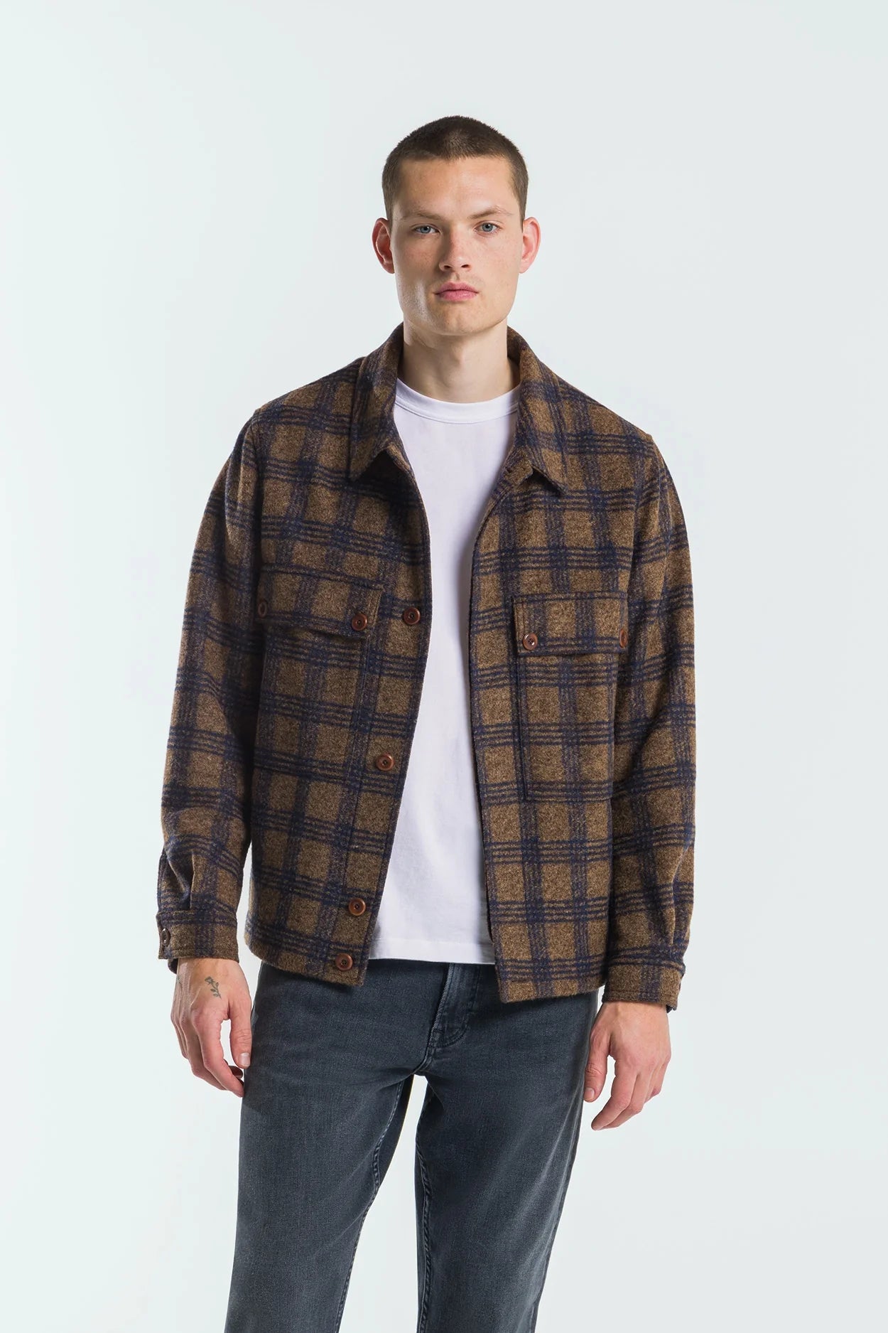 Man wearing a plaid shirt over a white t-shirt on a white background