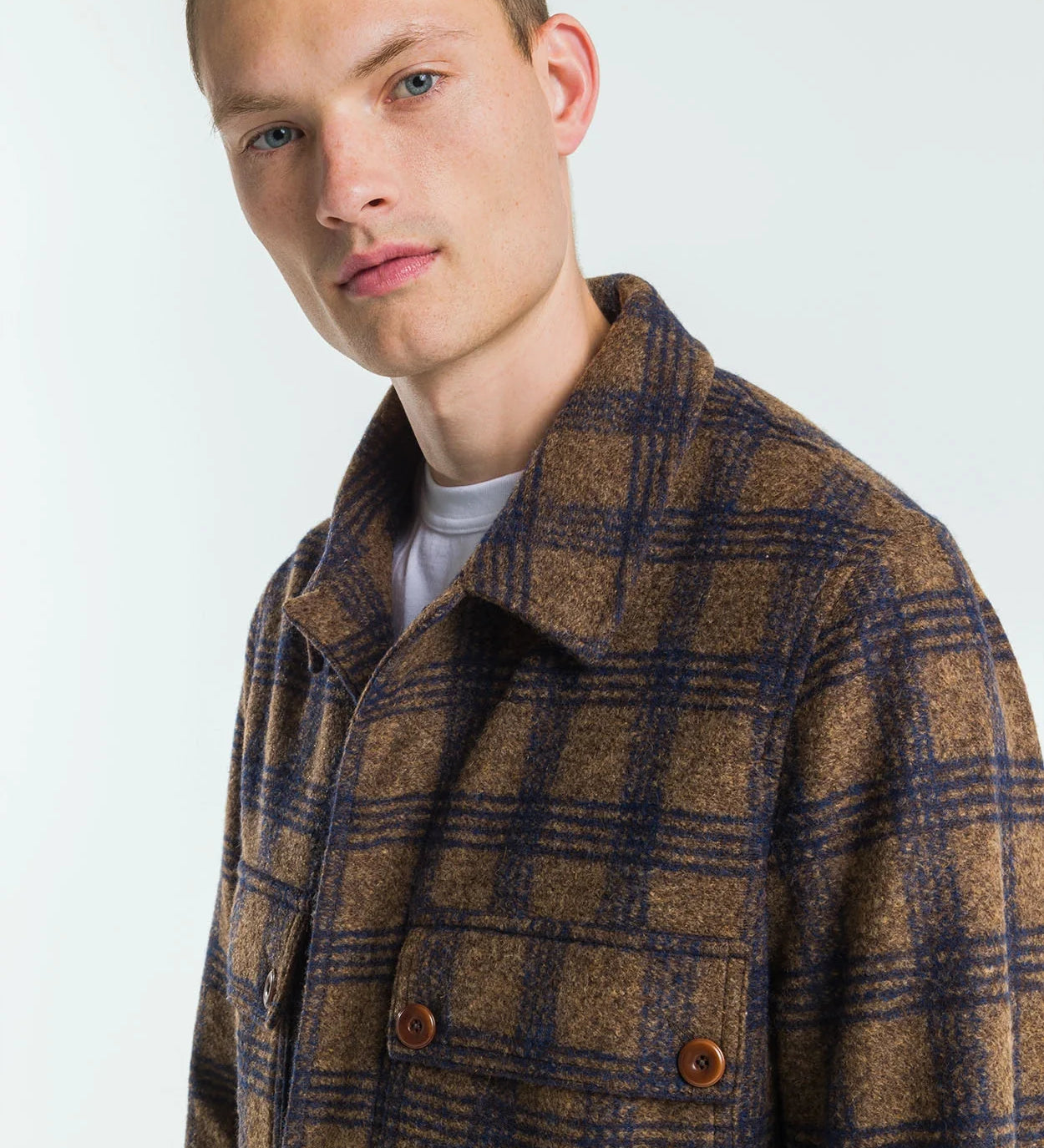 Man wearing a brown and blue plaid coat against a white background