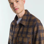 Man wearing a brown and blue plaid coat against a white background