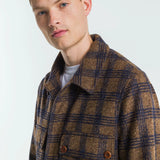 Man wearing a brown and blue plaid coat against a white background