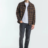 Man wearing a plaid shirt, white t-shirt, gray jeans, and white sneakers on a white background