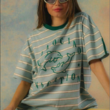 Person wearing a striped t-shirt with text and graphics on a textured wall background