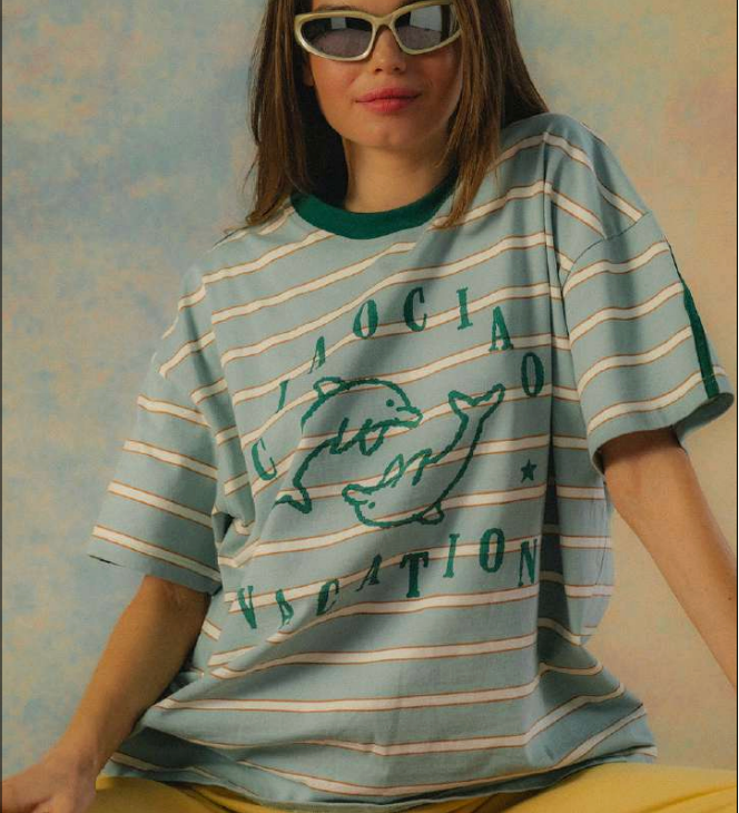 Person wearing a striped t-shirt with text and graphics on a textured wall background