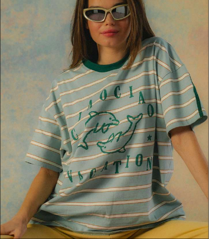 Person wearing a striped t-shirt with text and graphics on a textured wall background