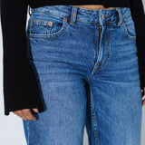 Blue jeans worn by a person on a plain background