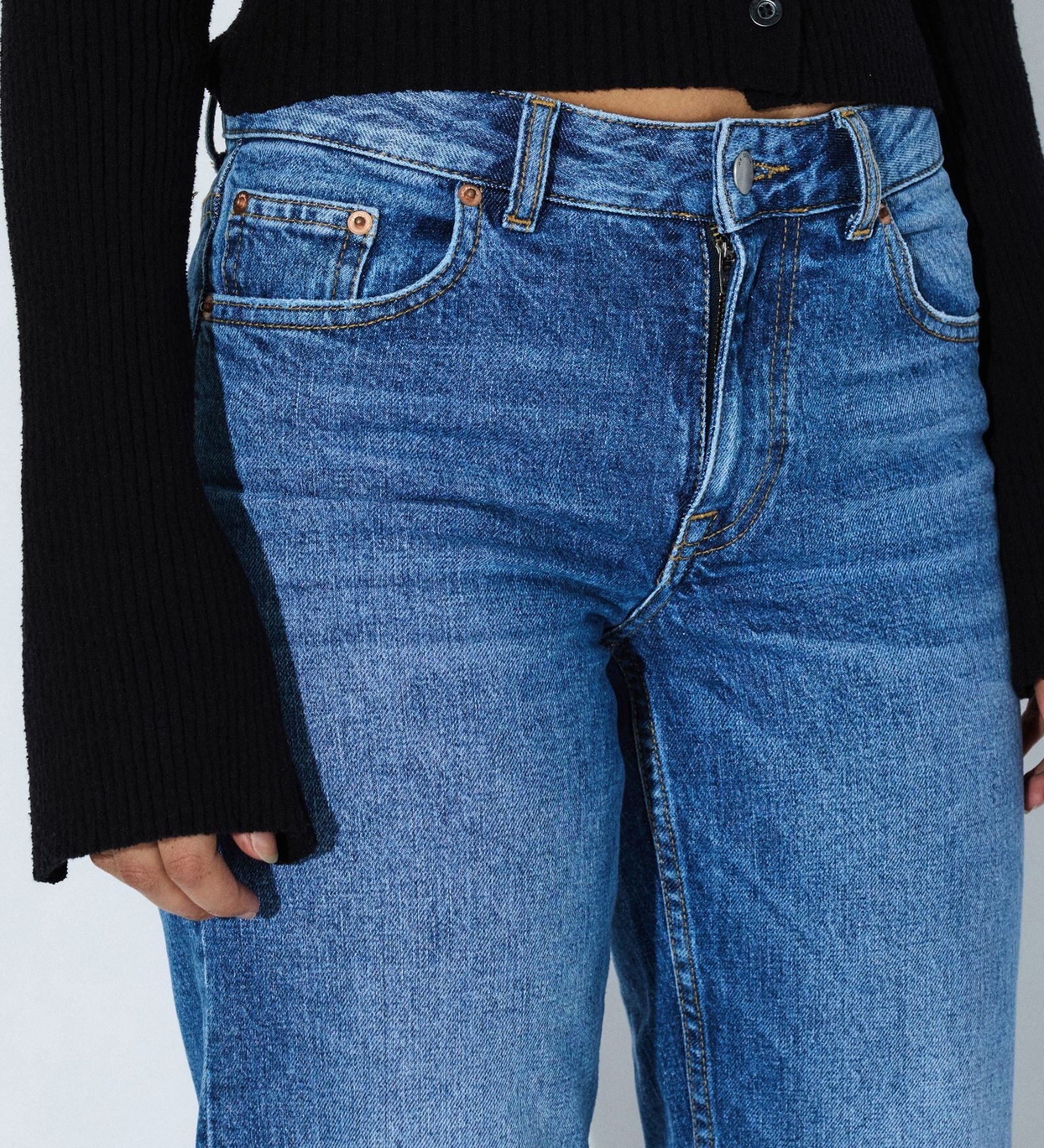 Blue jeans worn by a person on a plain background