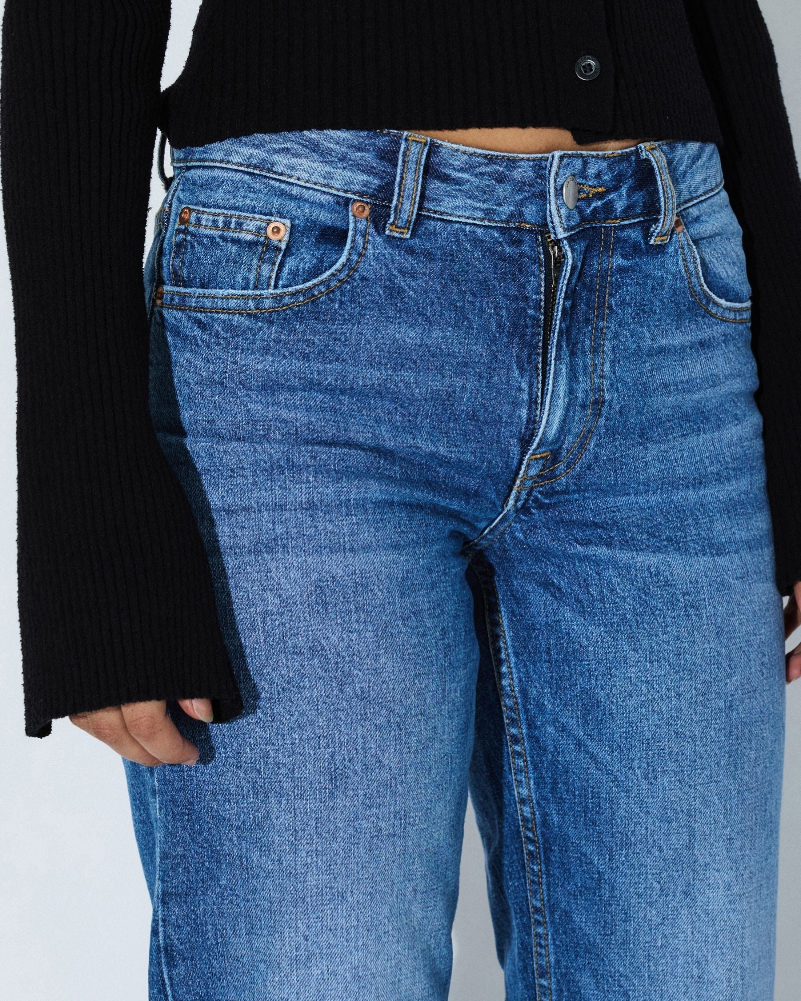 Blue jeans worn by a person on a plain background