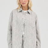 Woman wearing a light gray patterned shirt against a white background