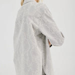 Woman wearing a light gray textured shirt and shorts on a white background