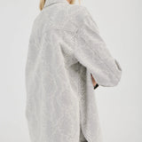 Woman wearing a light gray textured shirt and shorts on a white background