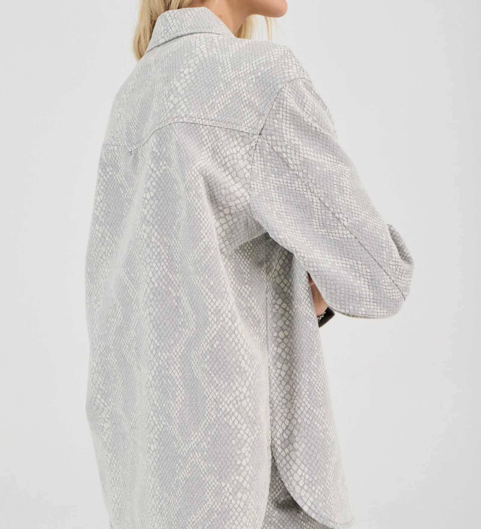 Woman wearing a light gray textured shirt and shorts on a white background