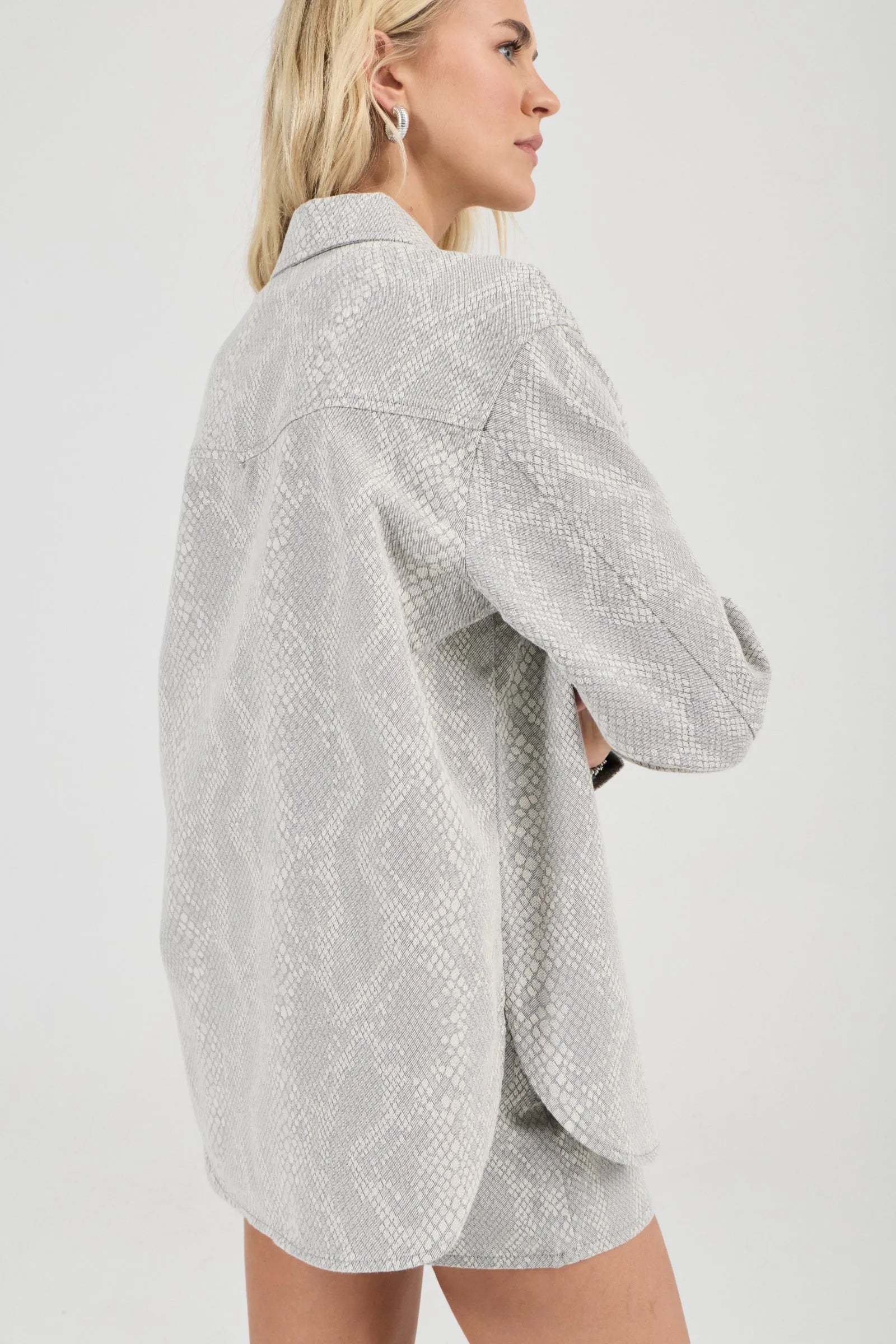 Woman wearing a light gray textured shirt and shorts on a white background