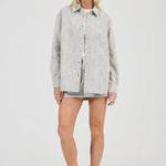 Woman wearing a light gray jacket over a white shirt on a white background