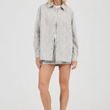 Woman wearing a light gray jacket over a white shirt on a white background