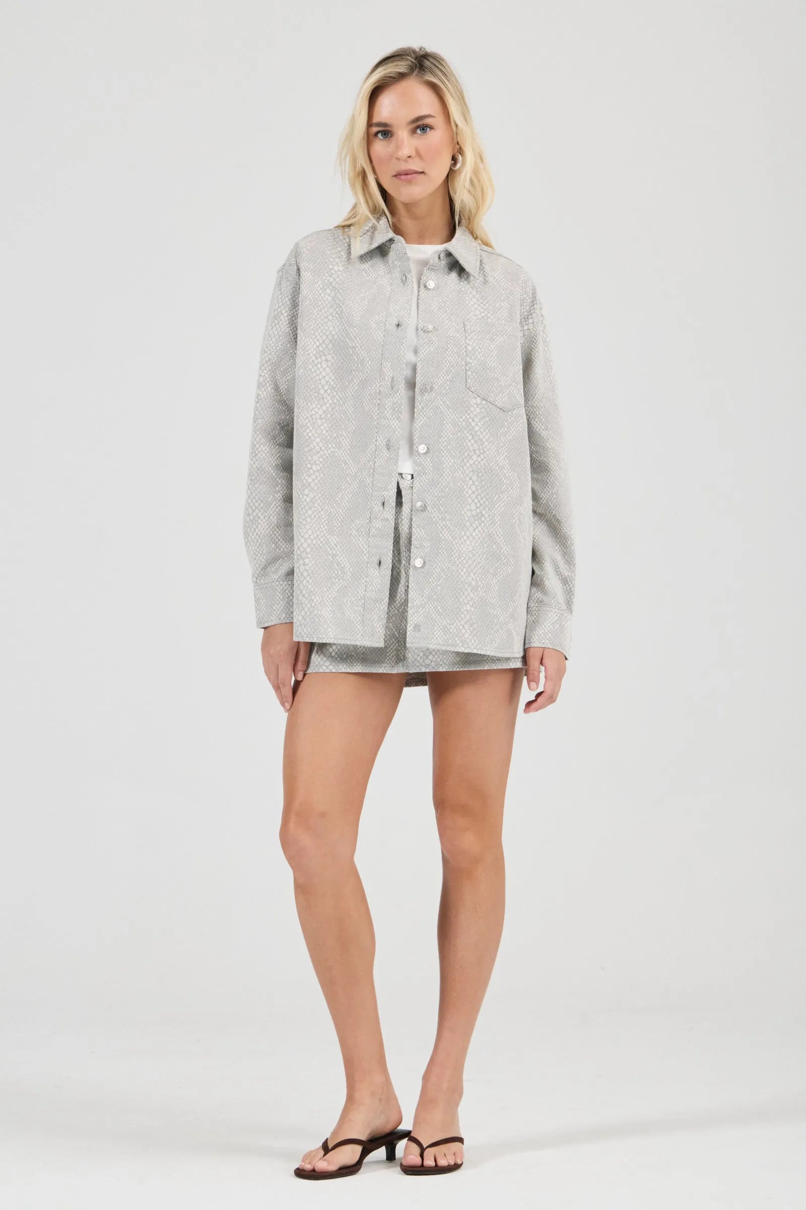 Woman wearing a light gray jacket over a white shirt on a white background