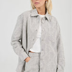 Woman wearing a gray textured jacket and skirt set on a white background