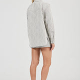 Person wearing a light gray oversized shirt on a white background