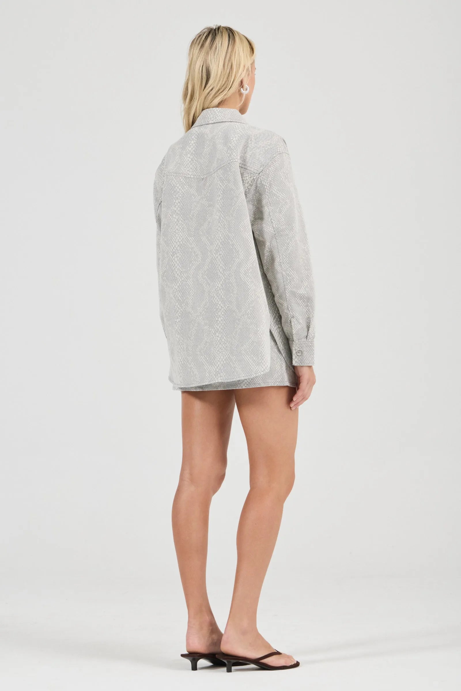 Person wearing a light gray oversized shirt on a white background