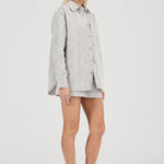 Woman wearing a light gray shirt and shorts on a white background