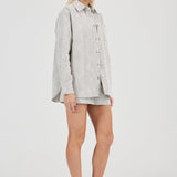 Woman wearing a light gray shirt and shorts on a white background