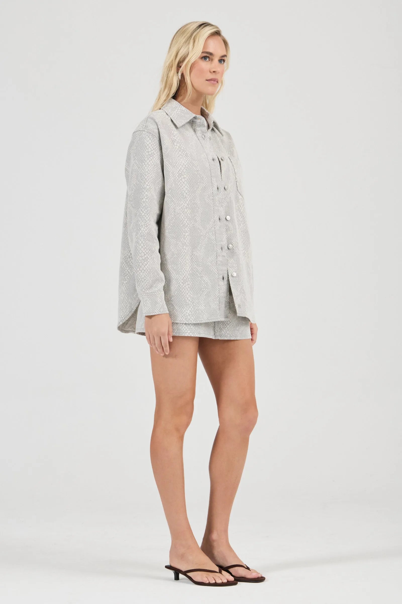 Woman wearing a light gray shirt and shorts on a white background