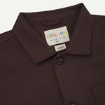 Close-up of a Dark Plum shirt collar with a label on a light gray background