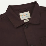 Close-up of a Dark Plum shirt collar with a label on a light gray background