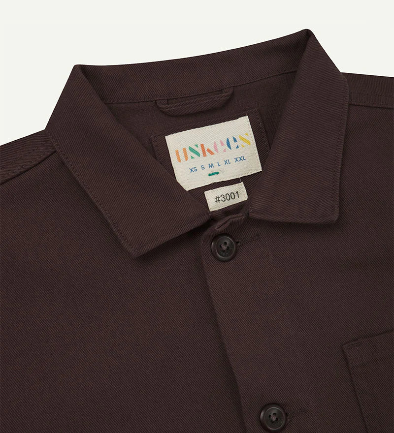 Close-up of a Dark Plum shirt collar with a label on a light gray background