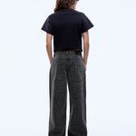 Person wearing a black t-shirt and dark patterned pants on a white background