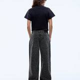 Person wearing a black t-shirt and dark patterned pants on a white background