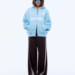 Person wearing a light blue hoodie with a brand logo and black pants on a white background