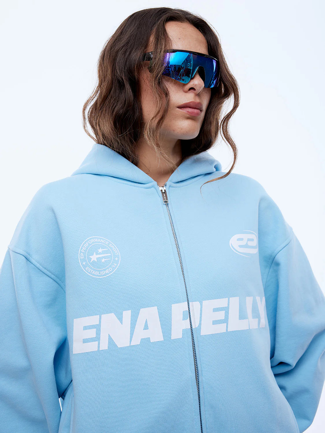 Person wearing a light blue hoodie with 'ENAPELLY' branding on a white background