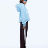 Person wearing a light blue hoodie and dark pants with white stripes on a white background