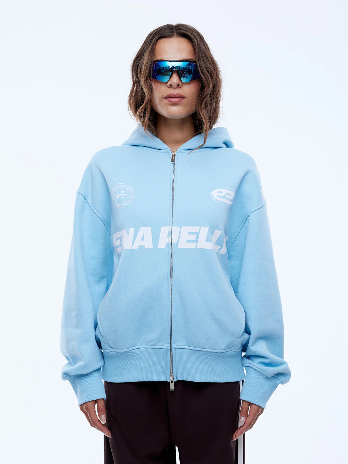 Person wearing a light blue hoodie with a brand logo on a white background
