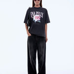 Person wearing a black t-shirt with a floral design and text, paired with black pants on a white background