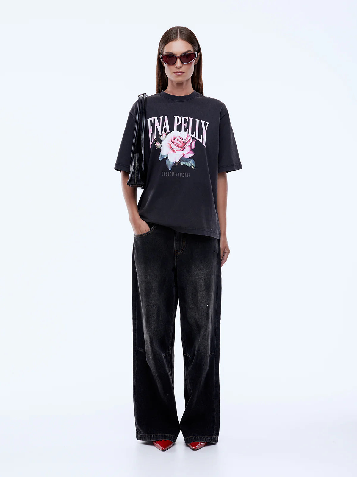 Person wearing a black t-shirt with a floral design and text, paired with black pants on a white background