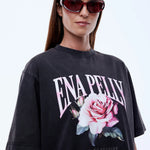 Person wearing a black t-shirt with a floral design and 'ENA PELLY' text on a white background