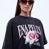 Person wearing a black t-shirt with a floral design and 'ENA PELLY' text on a white background