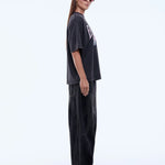 Person wearing a black oversized t-shirt and pants with red shoes on a white background
