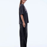 Person wearing a black oversized t-shirt and pants with red shoes on a white background