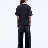 Person wearing a black t-shirt and wide-leg pants on a white background