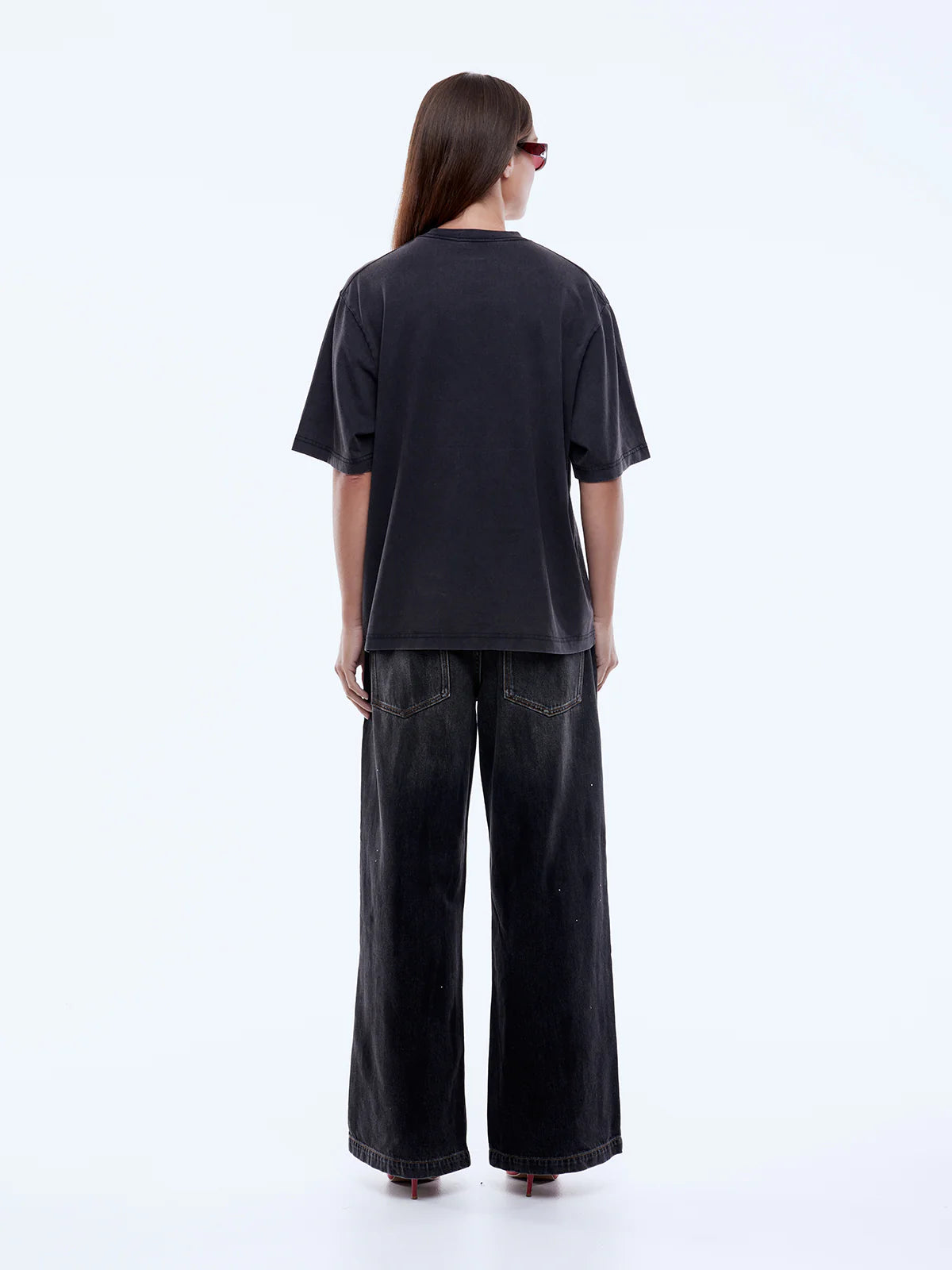 Person wearing a black t-shirt and wide-leg pants on a white background